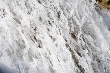Beyaz köpüklü şelale kaynayan suyuna yakın çekim. Dağ nehri şelalesi yosunlu taşların üzerinden akar. Doğa ve doğal güzellik kavramı