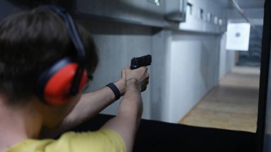 Atış menzilindeki hedefe nişan alan taktik kulaklıklı bir adam. Atış talimi atış poligonunda. Aşırı hobi konsepti