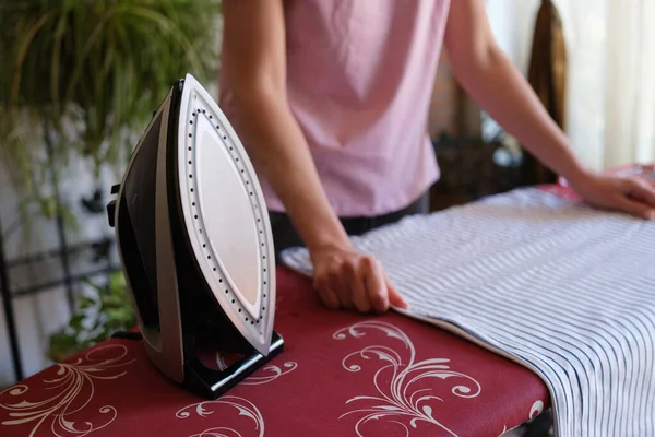 Close-up of housewife ironing bed linen on special board. Woman irons clothes. Housekeeping or housework and household chores concept