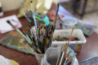 Ressam işyerindeki gözlüklü fırçaların üst görüntüsü. Sanat, resim ve çizim dersleri konsepti