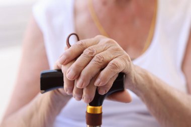 Ahşap baston tutan yaşlı kadınların yakın çekimi. Destek çubuğu kullanan yaşlı bir kadın. Yaşlılık ve bunaklık kavramı