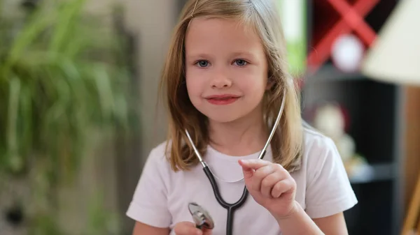 Retrato Menina Sorridente Usando Estetoscópio Médico Apontando Com Dedo Alguém — Fotografia de Stock