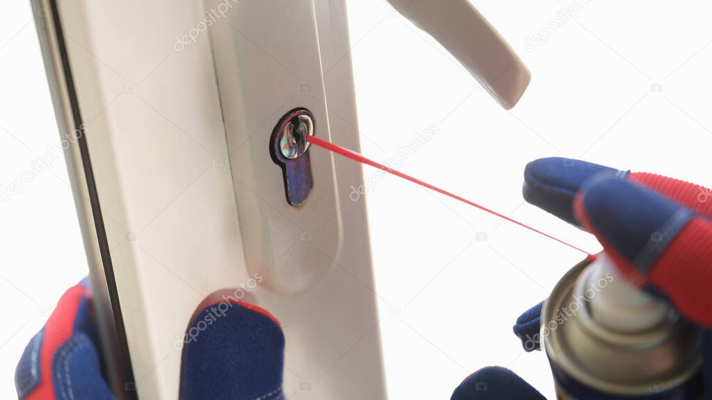 Close-up of handyman applying lubricate for lock of plastic window. Maintenance checks of pvc windows