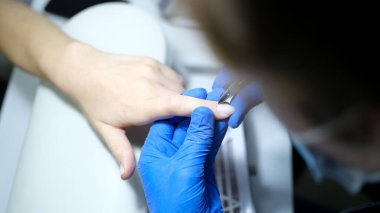 Özel aletler kullanarak müşteriye manikür yapan manikürcü uzmanına yakın çekim. Güzellik günü ve vücut bakımı konsepti