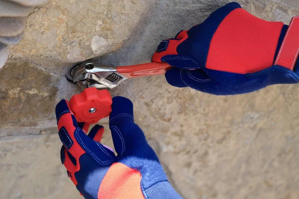 Close-up of male hands in work gloves repairing tap outside using wrench. Central water supply system concept