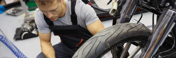 차고에서 작업복을 남자가 오토바이 근처에 타이어 기압을 조사함 — 스톡 사진