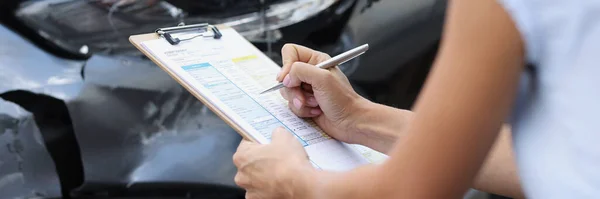 Eine Frau Einem Kaputten Auto Füllt Ein Dokument Aus Großaufnahme — Stockfoto