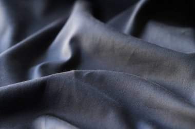 Top view of black wavy fabric textured background, cloth texture backdrop. Dark cloth for sewing. Beautiful crumpled pattern