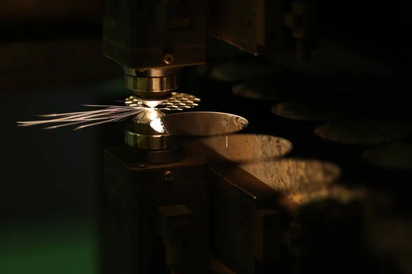 Close-up of laser machine cutting metal sheet and neon sparks flying out. Manufacturing and production concept