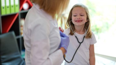 Portrait of happy smiling girl using medical stethoscope at doctor appointment. Healthcare, medicine and childrens hospital concept