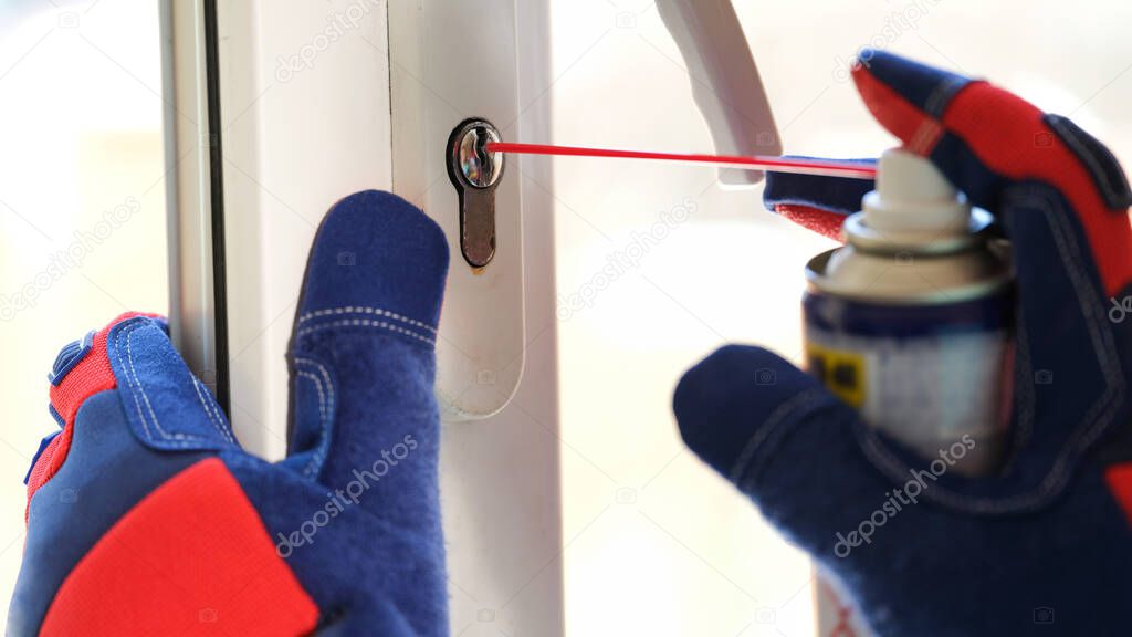 Close-up of man applying lubricate oil for lock of plastic window. Maintenance checks of pvc windows