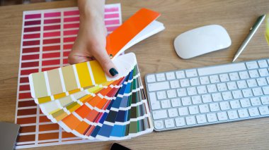 Top view of female interior designer showing fan of colourful samples. Woman searching proper colour for promotion. Design and art concept