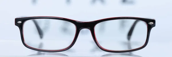 Glasses in black frame lying on background of eye test table closeup. Correction of myopia and hypermetropia concept