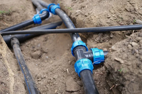 Connecting water supply closeup on background of earth. Garden sewer and watering system