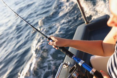 Balıkçı adamın elini yakalamak için kayıkta otururken oltayla oltayı tutuyor. Deniz balıkçılığı ve hobi