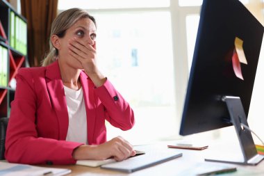 Bilgisayar ekranına bakarken şoke olmuş bir iş kadını. Bilgisayar arızası ve rapordaki iş hatasından rahatsız olan iş kadını