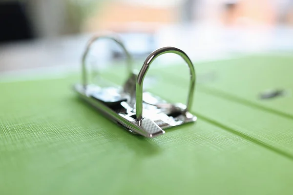 Green folder with metal clip on table. Stationery concept