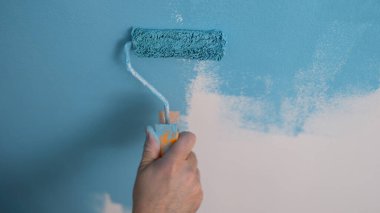 Ev boyacısı duvarları maviye boyar ve paten kayar. Duvarları onarma ve boyama kavramı