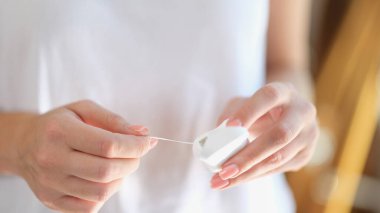 Kadın diş ipi ve paketi yakın çekimde tutuyor. Ağız hijyeni ve diş bakımı kavramı