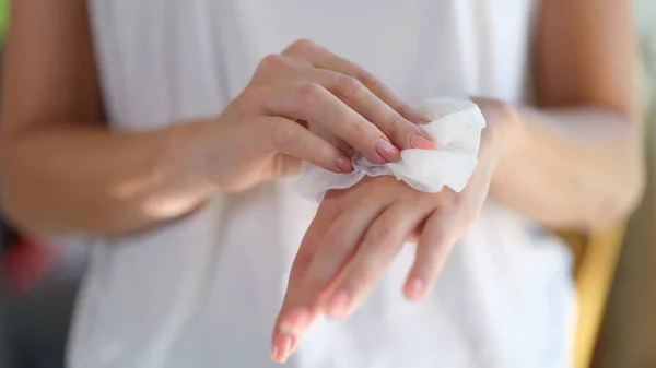 Right hand wipes left hand with piece of damp cloth closeup. Wet antibacterial hand wipes