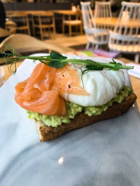 Avokado, tereyağı, zeytin, şifalı otlar ve somon balıklı sandviç.