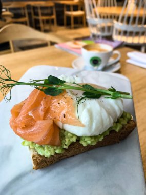 Avokado, tereyağı, zeytin, şifalı otlar ve somon balıklı sandviç.