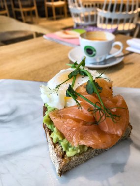 Avokado, tereyağı, zeytin, şifalı otlar ve somon balıklı sandviç.