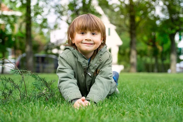 Retrato Menino Pré Escolar Vestindo Parka Verde Deitado Gramado Dia — Fotografia de Stock