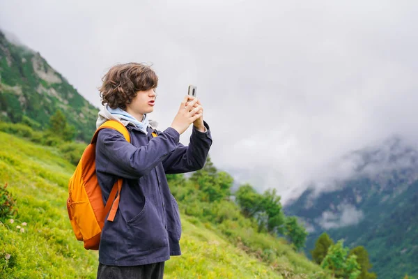 Nastolatek Robiący Zdjęcie Swoim Smartfonie Podczas Wędrówki Górach Chłopiec Kręconymi Zdjęcia Stockowe bez tantiem