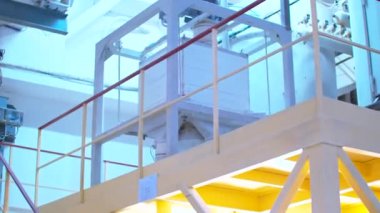 Yiyecek fabrikasında kullanılan büyük beyaz bir endüstriyel yapının etrafında dolaşıyorlar.