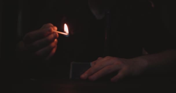 Tmavá scéna s rukama nepoznatelného muže vznítí zápalku před ohněm na svíčce — Stock video