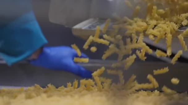 Kijkend naar de handen van de werknemer controleren de kwaliteit van pasta vallen om transportband schudden — Stockvideo