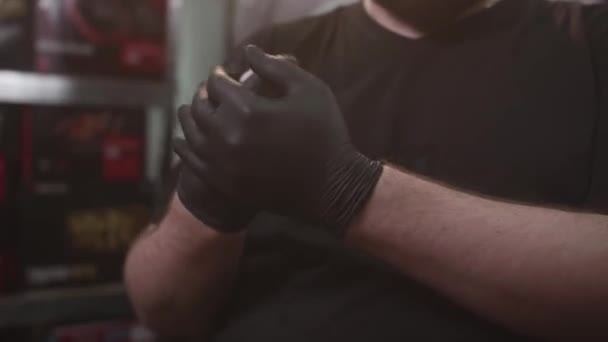 Una persona irreconocible se sienta frente a una cámara y se lava las manos con guantes negros — Vídeos de Stock
