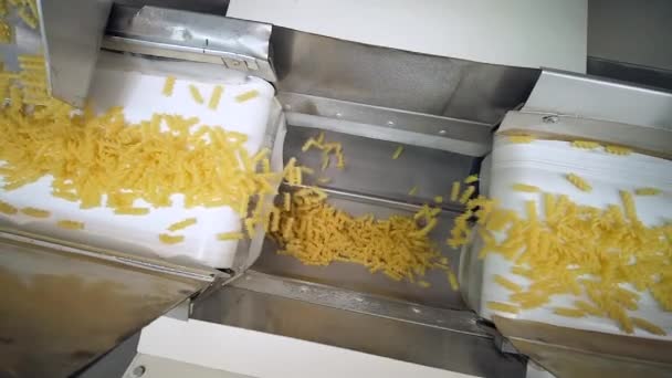 Two white conveyor belts move raw pasta to another one wave shaped conveyor — Stock Video
