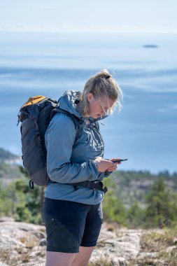 Kayıp ve endişeli açık hava genç beyaz kadın cep telefonu kapsama alanı arıyor. Yüksek Sahil Skuleskogen Ulusal Parkı İsveç 'in vahşi doğasında hayal kırıklığına uğramış görünüyor..