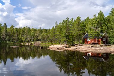 Stunning view of Serene and Reflecting Lake Tarnattvattnen and Remote hiking Resting Cottage in Skuleskogen National Park on a Summertime Evening with gorgeous background of Slattdalsskrevan. 