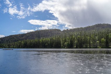 Skuleskogen Ulusal Parkı 'ndaki Serene ve Reflecting Tarnattvattnen Gölü ve Uzaktan Yürüyüş Kulübesi Slattdalskrevan' ın muhteşem arka planına sahip bir yaz akşamı. 