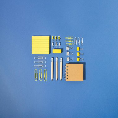 Eylül, okula dönüş, ofis konsepti. Çeşitli okul / ofis malzemeleri. Kare düzenleme kalemleri, kasetler, silgiler, raptiyeler, cetveller, keçeli kalemler, ataçlar, post-tit notlar, notlar. Parlak mavi arkaplan.