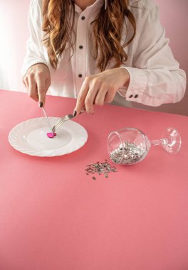 Aşk ve Sevgililer Günü kavramı. Aşkı yiyip bitiriyor. Tabağında pembe bir kalp ve bir bardak dolusu pırıl pırıl kalp olan bir kız. .