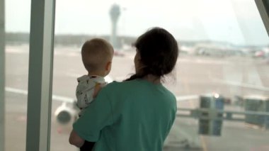 Mom with her son looking at airplane in airport.
