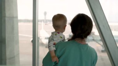 A mother and her child approach the window at the airport. 