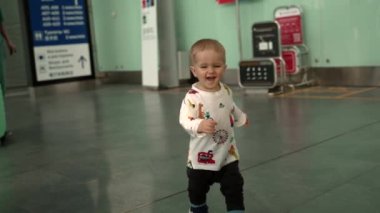Happy kid running at camera indoor of airport terminal.