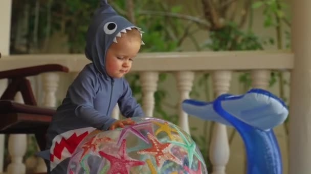 Крупный план ребенка играет с резиновыми надувными игрушками за пределами комнаты — стоковое видео