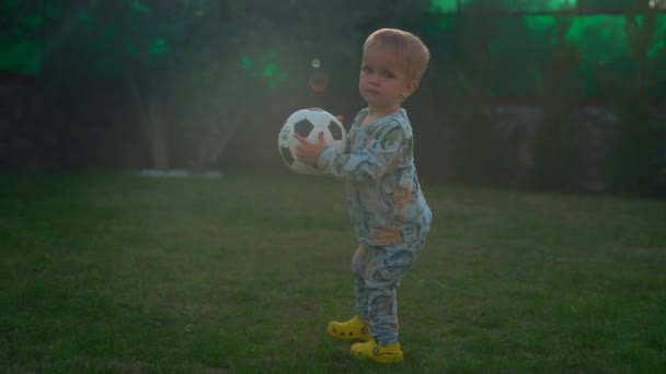 Cute Blond Boy Holds Soccer Ball Walking Green Grass Backyard — Vídeo de Stock