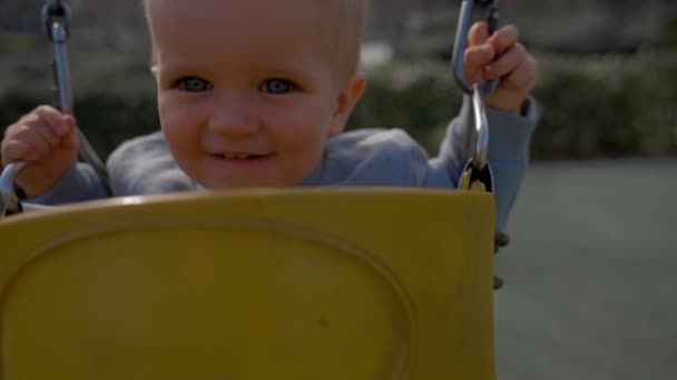 Веселий Хлопчик Катається Гойдалках Розмитому Тлі Блондинка Малюк Насолоджується Активністю — стокове відео