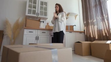 Conceited courier kicks paper boxes by feet causing mess in modern kitchen. Young woman gets shocked of delivery service and behavior of firm employee