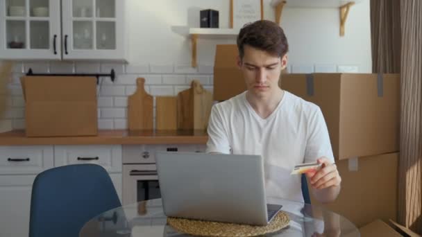 Young Man Makes Online Purchases Laptop Sitting Table Kitchen Paper — Stockvideo