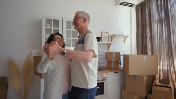 Happy Elderly Couple Enjoys Dancing Unpacked Paper Boxes Kitchen Relocation — Stockvideo