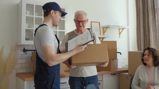 Courier Brings Cardboard Box New Apartment Senior Couple Asking Sign — Stockvideo