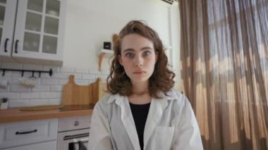 POV of brunette woman getting surprised after refuse at online job interview. Young lady with shocked facial expression sits at kitchen table closeup